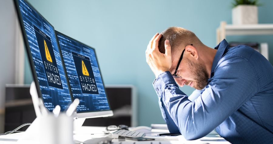 Business Man With Head in Hands in Front of Computer Due to Commercial Cyber Crime